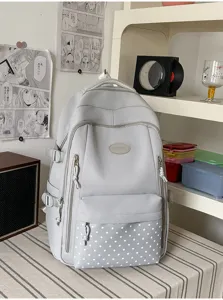 Sac à dos gris présenté debout, avec poche avant à motifs d’étoiles et petite étiquette ovale
