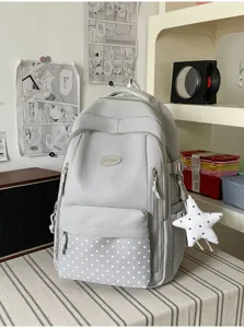 Sac à dos gris avec poche avant à étoiles et breloque étoile suspendue, posé sur une table rayée