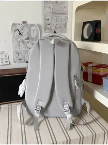 Vue arrière d’un sac à dos gris, avec bretelles rembourrées, boucles et poche latérale zippée
