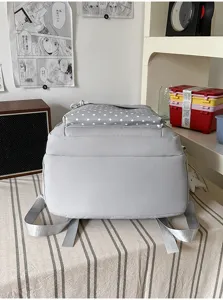 Vue arrière d’un sac à dos gris, avec dessus blanc à étoiles et bretelles assorties
