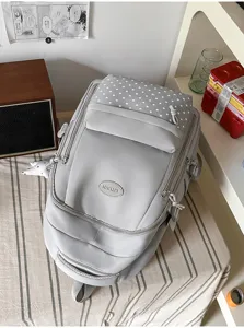Sac à dos gris avec panneau étoilé, compartiments zippés et cordons décoratifs visibles