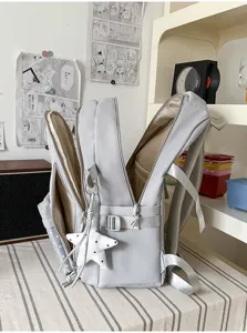 Vue latérale du sac gris clair ouvert, avec compartiments zippés, dos en mesh et breloque étoile