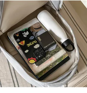 Vue intérieure d’un sac à dos gris avec livres, carnet, téléphone et bouteille isotherme blanche