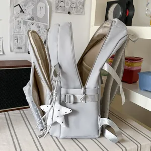 Sac à dos gris clair avec bretelles rembourrées en mesh, plusieurs compartiments et breloque étoile