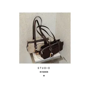 Two bags in beige and coffee brown with a suede-like finish, long shoulder straps and decorative charms