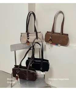 Four suede-textured bags in beige, brown and black arranged on a metal chair against a wall