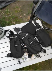 Outdoor flat-lay showing black chest harness with mesh panel, reflective strip, pockets and buckles