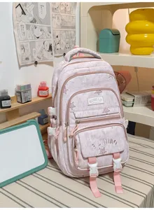 Sac à dos rose à motif clair, avec plusieurs poches zippées et des sangles, posé sur un bureau