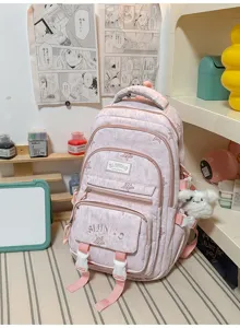 Vue de face d'un sac à dos rose pâle avec plusieurs poches zippées, des sangles roses et un pompon doux