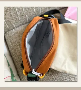 Gros plan sur la fermeture éclair ouverte, la doublure grise et le curseur blanc du sac orange