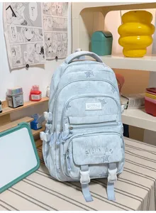 Sac à dos bleu clair en tissu délavé, avec plusieurs poches zippées et des boucles à l’avant.
