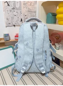 Vue arrière d’un sac à dos bleu clair effet denim, avec bretelles rembourrées et motifs étoilés