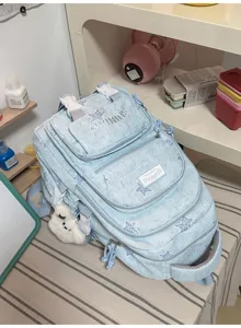 Détail du sac bleu clair délavé, à étoiles, avec poches zippées et pendentif en peluche