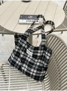 Close-up of a black-and-white plaid tote with fine yellow lines, displayed on an outdoor chair