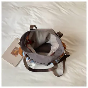 Vue de dessus du sac ouvert, avec intérieur clair, empiècements bruns et bandoulière visible