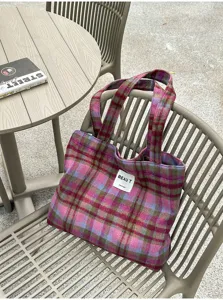 Plaid pink and purple woven tote with double handles, shown on an outdoor chair seat