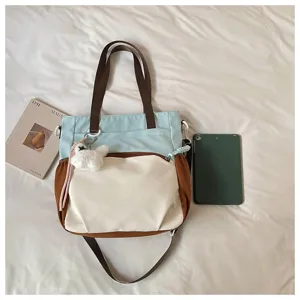 Sac en tissu coloré, poignées brunes et sangle réglable, près d’un livre et d’une tablette