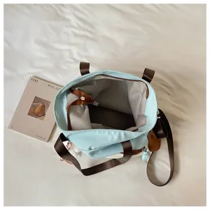 Sac bleu clair ouvert vu du dessus, avec sangles brunes, zip et poches intérieures couleur crème