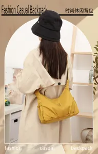 Vue de dos d’un modèle portant un sac jaune moutarde froncé en nylon, à fermoir rond en métal