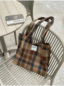 Brown, orange and blue plaid fabric tote with twin handles, photographed on an outdoor chair
