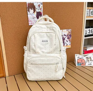 Vue de face du sac crème à pois, avec deux poches zippées, des sangles latérales et une poignée