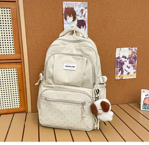 Vue d’un sac à dos ivoire avec texture à petits points, poches avant et porte-clés chien en peluche