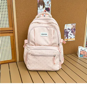 Sac à dos rose à petits pois, avec poignée et bretelles, présenté sur une table en bois