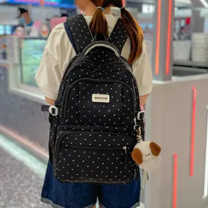 Sac à dos léger et spacieux à pois blancs, porté de dos avec un petit pendentif en peluche