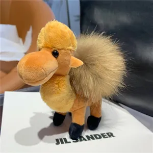 Plush camel keychain displayed on a gift box, with a fluffy light-brown hump and black feet