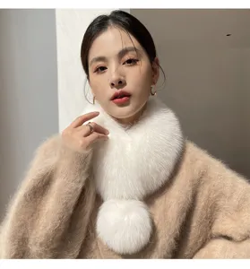 Model wearing a white fluffy loop scarf with a large pom-pom, styled with a beige knit sweater