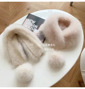 Close-up of a plush light beige scarf with matching pom-poms and a softer taupe reverse side