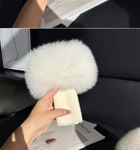 Close-up of a white fluffy pom-pom attached to a ribbed knit cover, held inside a car