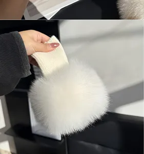 Close-up of a fluffy white fur cuff with an ivory knitted band, held up by hand