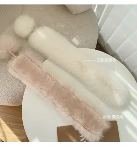 Close-up of a white fur strip beside its blush pink reverse, with two fluffy pom-pom accents