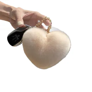 Llavero de corazón de pelo sintético marfil con cadena dorada, mostrado en la mano para bolsos
