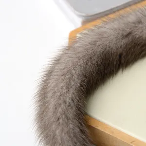 Primo piano di pelliccia grigio-bruna lungo un bordo di legno chiaro, accanto a una superficie crema