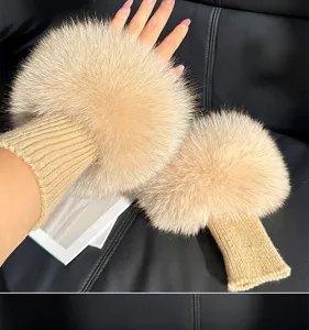 Close-up of two beige fluffy wrist warmers with ribbed knit cuffs displayed against a dark seat