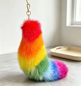 Close-up of a rainbow-gradient fluffy tail charm with a red tuft and gold-tone chain clasp