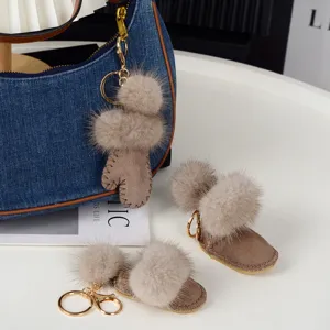 Gros plan sur des pompons doux, avec pendentifs bottine et moufle en suédine et anneaux dorés