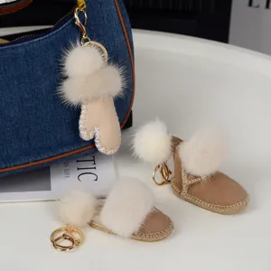 Pompons ivoire, gant beige et bottillon en daim avec des crochets dorés près d’un sac en jean