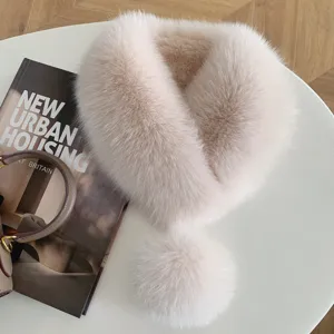 Overhead view of a soft blush-and-white fluffy scarf with a matching pom-pom on a round table
