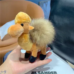 Close-up of a yellow-brown plush camel with a fluffy light-brown hump, held in a hand
