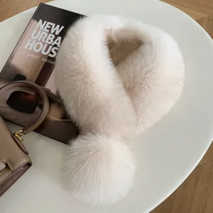 Flat lay of a fluffy ivory fur collar with a rounded pom-pom and soft beige shading