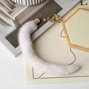 Vista dall’alto di un pendente bianco in pelliccia, con gancio dorato e chiusura metallica con strass