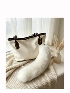 White fluffy tail-shaped charm with a gold clasp hanging from an ivory tote with brown trim
