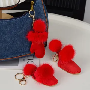 Détail de breloques rouges en forme de gant et de bottine, avec pompons doux et attaches dorées