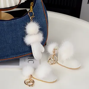 Figurine et bottines en peluche blanche avec crochets dorés, présentées près d’un sac en denim bleu
