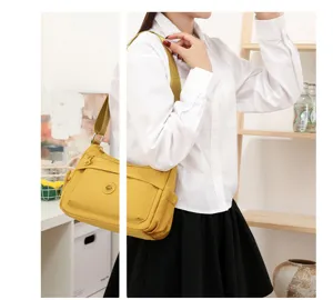 Dettaglio di una donna che sistema la tracolla della borsa gialla, con tasca anteriore con zip