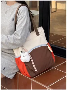 Vue de côté du cabas en toile à panneaux contrastés, avec anses brunes et petit lapin blanc en peluche