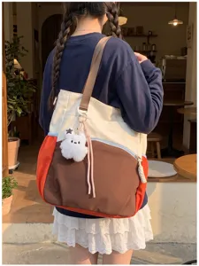 Vue de dos, un modèle porte un cabas coloré avec ourson en peluche et pompon rose dans un café